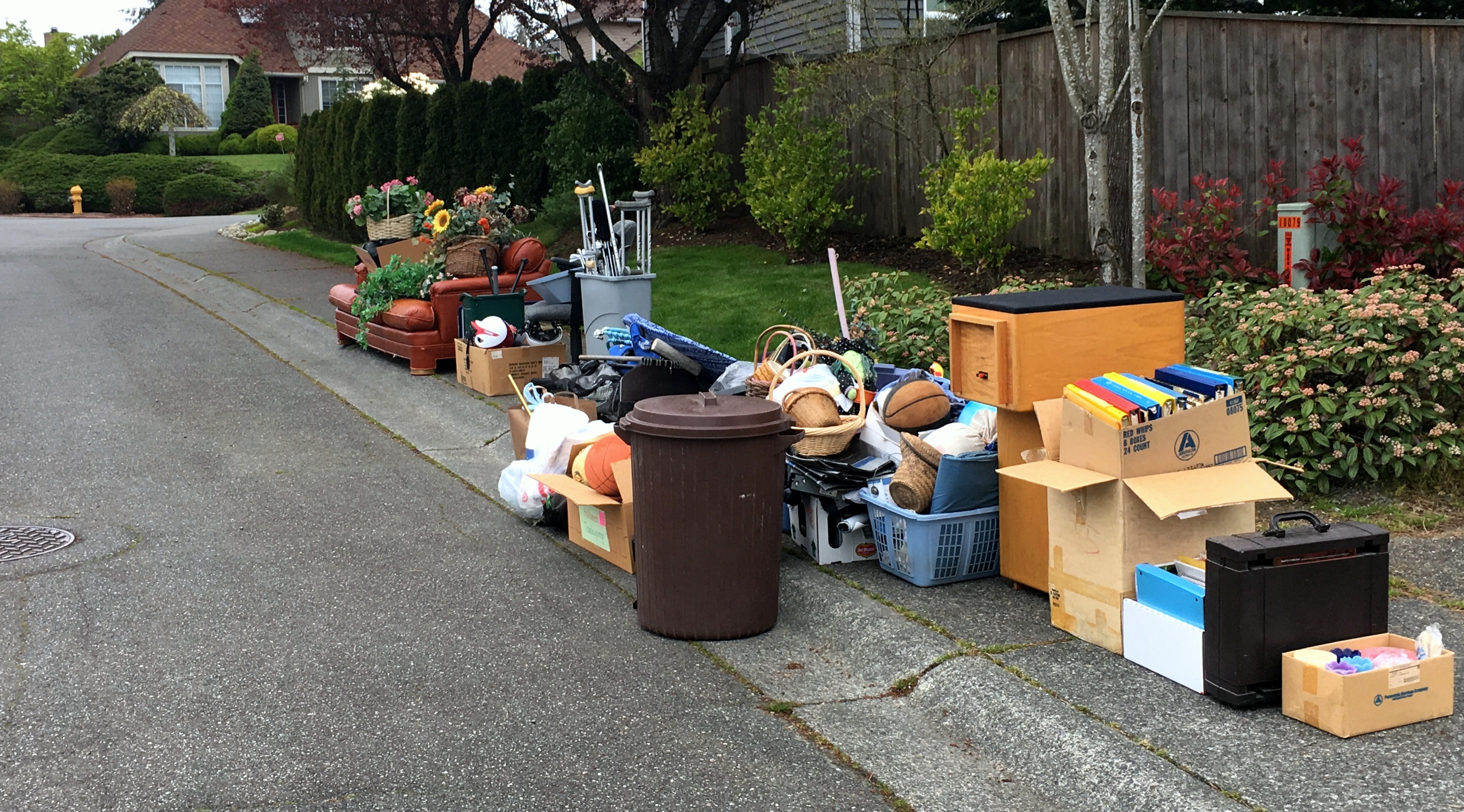 boxes, garbage, chairs and trash ready at curb to be picked up by garbage truck