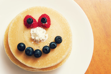 stack of pancakes with bluberry smile and strawberry eyes